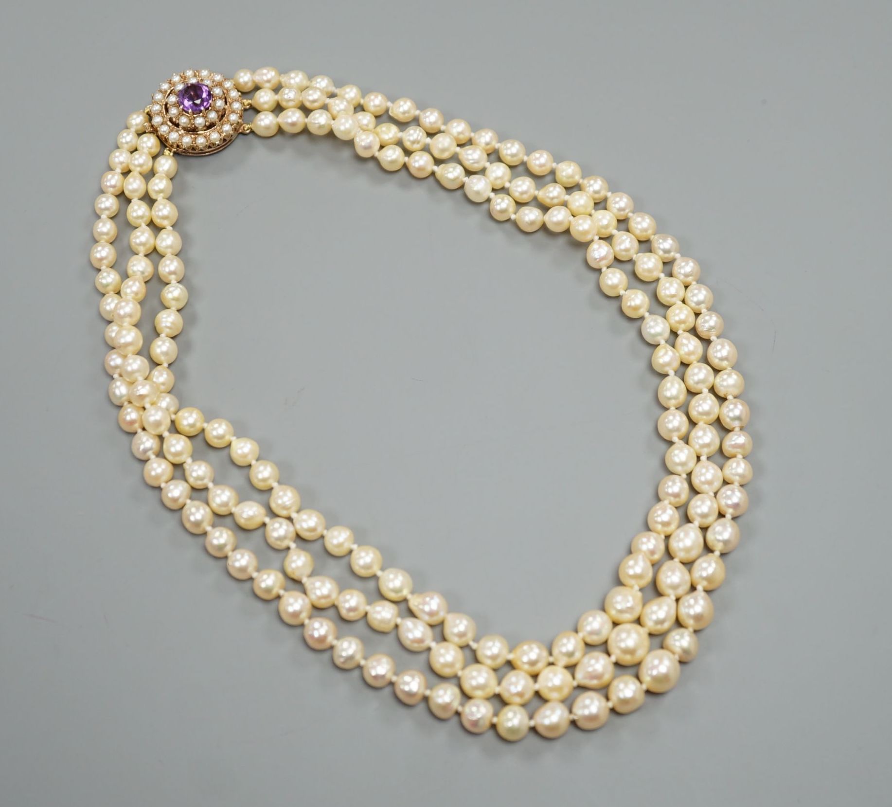 A triple strand cultured pearl choker necklace, with a yellow metal, amethyst and cultured pearl set clasp, 44cm.